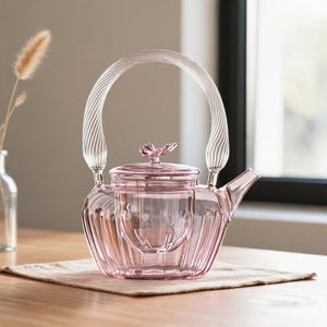 Puede incluir: Una tetera de cristal rosa translúcido con cuerpo acanalado, asa de cristal transparente con textura espiral retorcida y tapa rematada con un pequeño pomo en forma de flor rosa. La tetera incluye un infusor de cristal a juego.