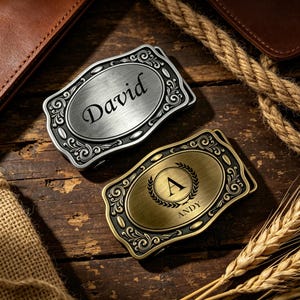 Peut inclure: Deux boucles de ceinture rectangulaires aux coins arrondis avec des bordures à volutes ornées. L'une est argentée avec le nom David gravé en écriture cursive. L'autre est en laiton avec une couronne de laurier, la lettre A et le nom ANDY.