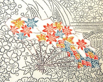 May include: A cream-coloured fabric featuring a black dotted pattern of floral and wave motifs. A central folding fan design displays vibrant red, orange, and blue maple leaves alongside a colourful, repeating wave pattern on its surface.
