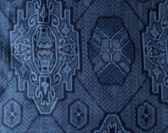 May include: A dark blue fabric featuring a repeating geometric pattern in lighter blue tones. The design consists of large, intricate, diamond-shaped motifs interspersed with smaller, hexagonal shapes, all rendered in a textured weave.