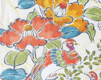 May include: A white fabric featuring a colourful botanical and avian print. The design includes large orange and yellow flowers with blue and green leaves, alongside two stylised birds with orange, blue, and green plumage on a white background.