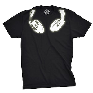 Puede incluir: Camiseta negra con un contorno blanco de unos auriculares en la parte delantera. La camiseta tiene una pequeña etiqueta en la parte delantera que dice "Crazy Dog".