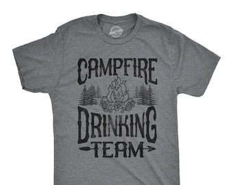 Könnte beinhalten: Ein meliertes graues T-Shirt mit einem schwarzen Aufdruck "Campfire Drinking Team". Das Design beinhaltet ein Lagerfeuer, Bäume und einen Pfeil. Das T-Shirt besteht aus einem weichen Material und hat einen Rundhalsausschnitt.
