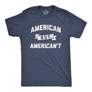 Puede incluir: Una camiseta azul marino con un gráfico blanco desgastado que dice "American Not American't".