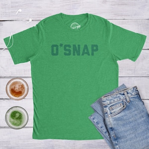 May include: Green t-shirt with a shamrock and the text "O'SNAP" printed on the front.