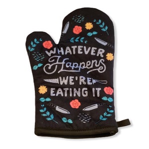 Puede incluir: Manopla de horno negra con un diseño floral y el texto "Whatever Happens We're Eating It".