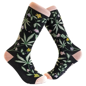 Könnte beinhalten: Ein Paar schwarze Kniestrümpfe mit einem Blumen- und Blattmotiv. Die Socken haben einen rosa Saum oben und unten.