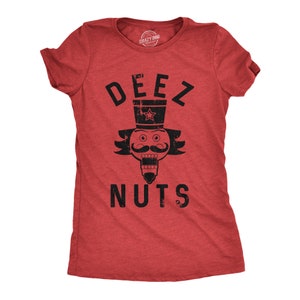 May include: Red t-shirt with a black graphic of a nutcracker with the text "DEEZ NUTS" printed on it.