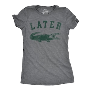 May include: A heather gray t-shirt with the word "LATER" printed in green above a green alligator graphic. The shirt has short sleeves and a crew neck. The brand logo "Crazy Dog" is visible on the upper back of the shirt.