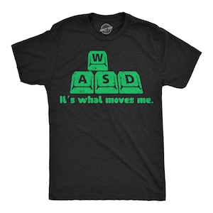 May include: A black t-shirt with a green graphic of the letters "WASD" on a keyboard. The text "It's what moves me." is printed below the graphic.