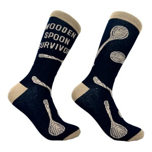 May include: A pair of black socks with a beige cuff and a pattern of wooden spoons. The socks have the text "Wooden Spoon Survivor" on one sock.