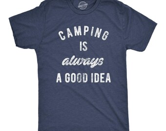 May include: A navy blue short-sleeve t-shirt with a heathered texture. The front features white distressed-style text that reads CAMPING IS always A GOOD IDEA. The shirt has a crew neckline and a standard fit, with a small brand logo at the inner neck.