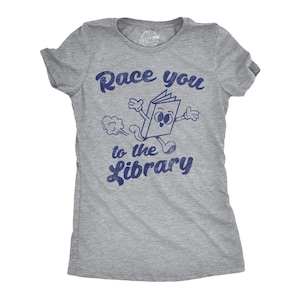 Op de afbeelding: Grijs T-shirt met een blauwe afbeelding van een lopend boek met de tekst "Race you to the library".