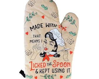 May include: A beige oven mitt featuring a graphic of a person wearing a chef hat, holding a spoon, and winking. The text reads: MADE WITH LOVE... THAT MEANS I LICKED THE SPOON & KEPT USING IT. The design includes small red hearts and green sprigs.