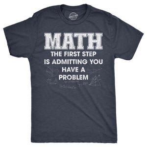 May include: Dark navy blue t-shirt with the text "MATH THE FIRST STEP IS ADMITTING YOU HAVE A PROBLEM" in white. The shirt also features math symbols and equations. A Crazy Dog brand logo is visible on the collar.