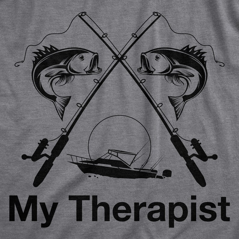May include: A gray t-shirt with a black graphic design of two crossed fishing rods with fish on the lines and a boat in the middle. The text "My Therapist" is printed below the graphic.