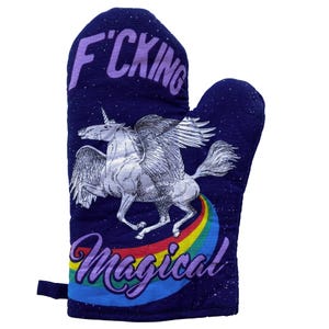 Op de afbeelding: Een donkerblauwe ovenwant met een witte gevleugelde eenhoorngrafiek, een kleurrijk regenboogspoor en de tekst "F*CKING MAGICAL" in het paars. De stof heeft een gespikkeld wit patroon dat doet denken aan een sterrenhemel over het oppervlak.