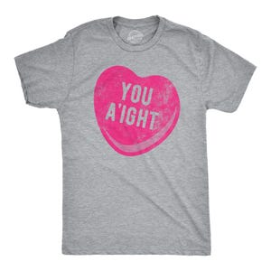 May include: A gray t-shirt with a pink heart-shaped candy design that says "You A'ight".
