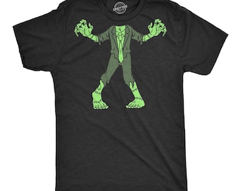 May include: A black short-sleeve t-shirt featuring a graphic print of a headless zombie figure in a suit and tie. The zombie is depicted in light green with visible stitches on its arms, legs, and neck area, standing with arms raised.