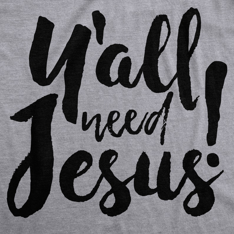 May include: A gray t-shirt with the phrase "Y'all need Jesus!" in large, black, cursive lettering. The text is centered and takes up most of the shirt's surface.