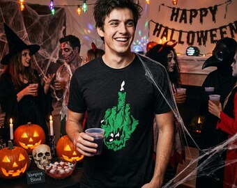 May include: A black short-sleeve t-shirt featuring a green graphic of a hand making an obscene gesture with a candle flame on the fingertip. The design includes a stylized face within the hand graphic, printed on a soft cotton-blend fabric.