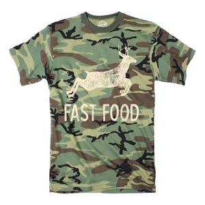 May include: A camouflage green t-shirt with a white silhouette of a deer jumping and the text "FAST FOOD" printed on the front.