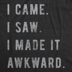 K&ouml;nnte beinhalten: Ein dunkelgraues T-Shirt mit wei&szlig;em Text, der "Ich kam. Ich sah. Ich machte es peinlich." lautet.