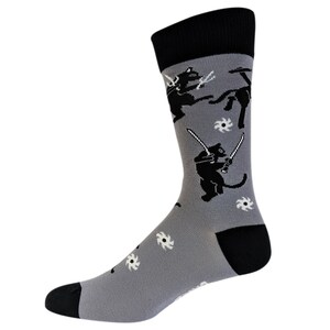 May include: Gray socks with a black and white pattern of cats wearing swords and throwing ninja stars.