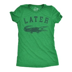 May include: Green t-shirt with the word "LATER" above a dark green alligator illustration. The shirt is a crew neck style and has short sleeves. The brand "Crazy Dog" is printed on the tag.