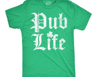 May include: A bright green short-sleeve t-shirt featuring the white distressed text "Pub Life" printed on the chest. The letter "i" in "Life" is replaced by a small white shamrock graphic. The shirt has a crew neckline and a heathered texture.