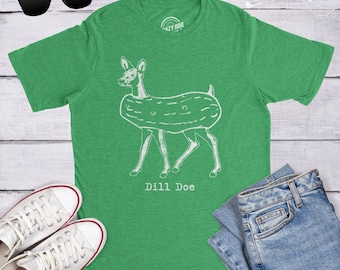 Peut inclure: Un t-shirt vert chiné avec un graphisme au trait blanc représentant un cerf portant un corps de cornichon. Le texte "Dill Doe" est imprimé en blanc sous le dessin. Le t-shirt présente un col rond et des manches courtes au design décontracté.