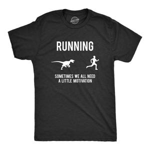 Puede incluir: Una camiseta de manga corta gris carbón con texto blanco serigrafiado que dice RUNNING y SOMETIMES WE ALL NEED A LITTLE MOTIVATION, acompañada de siluetas blancas de una persona corriendo lejos de un dinosaurio.