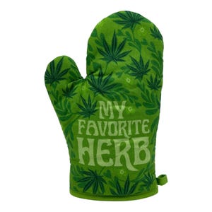 May include: A green oven mitt featuring a repeating pattern of dark green cannabis leaves and the text "MY FAVORITE HERB" printed in a lighter green, stylized font across the center of the mitt, which includes a small fabric loop at the base.