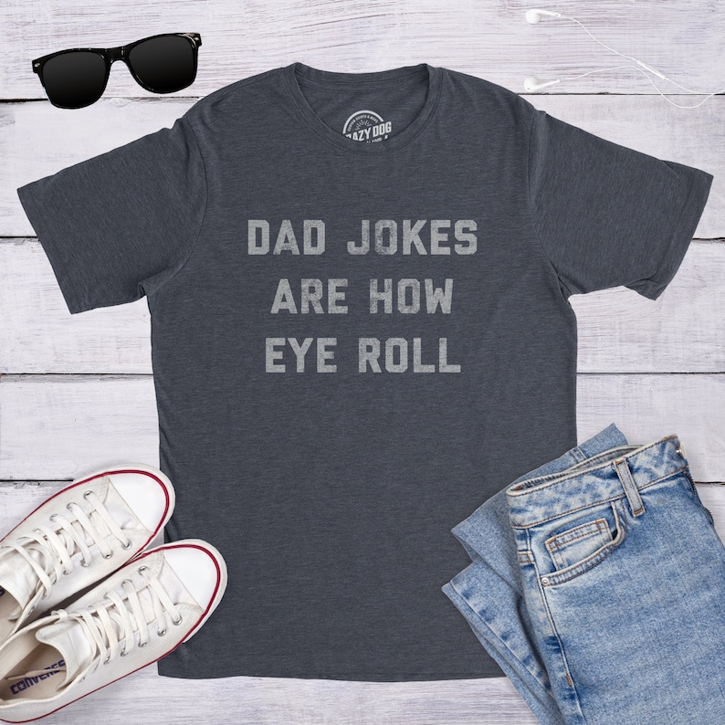 May include: A dark blue t-shirt with the text "DAD JOKES ARE HOW EYE ROLL" printed in white on the front.