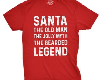 Może przedstawiać: Czerwona koszulka z krótkim rękawem z białym, postarzanym napisem: SANTA, THE OLD MAN, THE JOLLY MYTH, THE BEARDED LEGEND. Koszulka ma okrągły dekolt i standardowy krój, a grafika jest wyśrodkowana na wysokości klatki piersiowej.