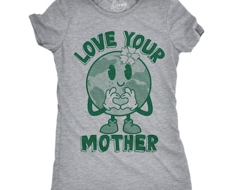 Peut inclure: Un t-shirt gris chiné à manches courtes avec un motif vert représentant une planète Terre souriante avec une fleur sur la tête, formant un cœur avec ses mains. Le texte "LOVE YOUR MOTHER" est imprimé en lettres vertes grasses au-dessus et en dessous.