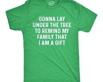May include: A heather green short-sleeve t-shirt with white distressed text printed on the chest that reads: GONNA LAY UNDER THE TREE TO REMIND MY FAMILY THAT I AM A GIFT. The shirt features a crew neckline and a standard fit design.