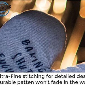 May include: Blue oven mitt with the text "Baking Sh*t Up" embroidered on it. The mitt has a detailed design with fine stitching.