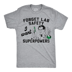May include: A heather gray t-shirt with a graphic that reads "Forget Lab Safety, I want Superpowers." The graphic features a scientist holding a green liquid in a vial. The shirt is a crew neck.