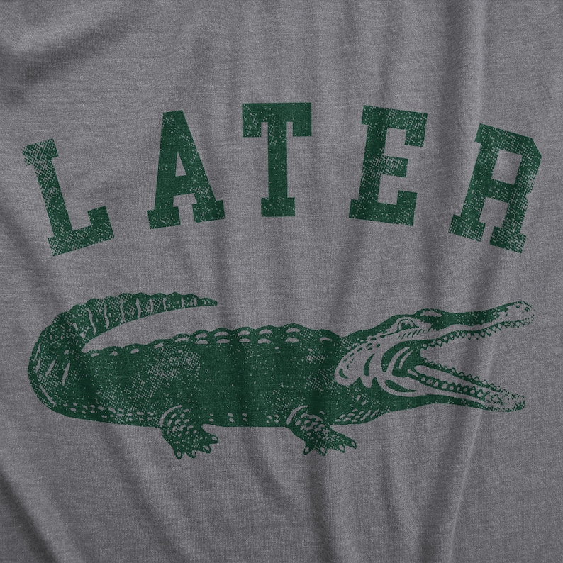 Puede incluir: Una camiseta gris con un gr&aacute;fico de cocodrilo verde y la palabra "LATER" impresa en verde.