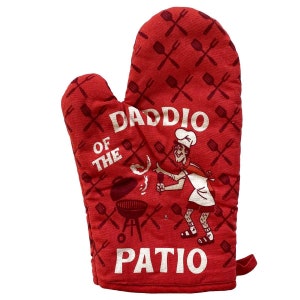 Op de afbeelding: Rode ovenwant met een witte afbeelding van een cartoonkok die grilt en de tekst "Daddio of the Patio".