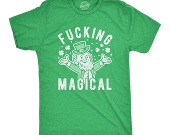 Puede incluir: Una camiseta de manga corta de color verde brillante con un gráfico blanco desgastado de un duende con sombrero de copa, rodeado de tréboles de cuatro hojas y destellos, con el texto FUCKING MAGICAL impreso en una fuente blanca y negrita.