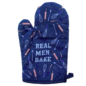 May include: A dark blue oven mitt featuring a repeating pattern of light blue and peach-colored kitchen utensils including whisks, rolling pins, and spatulas. The text "REAL MEN BAKE" is printed in large, light blue block letters in the center.