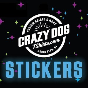 May include: A black and white logo with the text "Crazy Dog Tshirts.com Rochester, NY" and the words "Custom Shirts & More" in a circle around the logo. The text "STICKERS" is in blue letters on a black background with colorful stars.