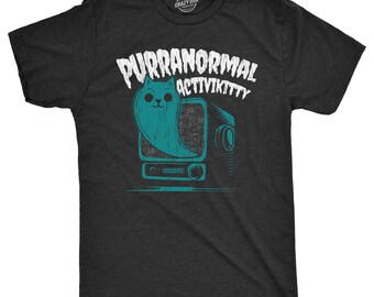 May include: A charcoal gray short-sleeve t-shirt featuring a teal graphic of a ghost cat emerging from a vintage television set. The text above the graphic reads PURRANORMAL ACTIVIKITTY in a distressed white font, with a small logo at the neck.