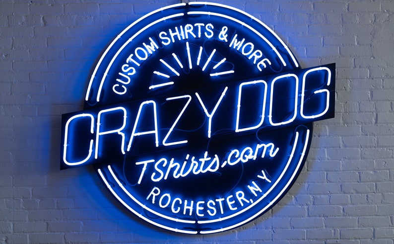 May include: A blue neon sign with a black background that reads "Crazy Dog Tshirts.com Rochester, NY" and "Custom Shirts & More".