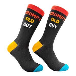 May include: A pair of black socks with the text "GRUMPY OLD GUY" in white and yellow. The socks have red cuffs, yellow heels, and blue toes. The socks are designed for comfort and style.