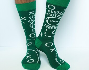 May include: A pair of dark green crew socks featuring a white graphic print of football play diagrams, including X's, O's, and dashed lines. The text "FANTASY FOOTBALL LEGEND" is printed in white across the fabric along with a football icon.