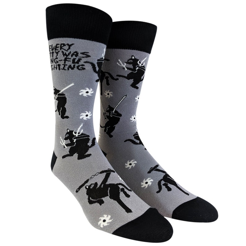 May include: A pair of gray socks with a black cat ninja design. The socks have the text "EVERY CITY WAS DOING-FU FIGHTING" on the top of the socks.