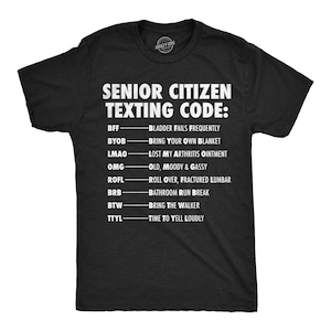 May include: Black t-shirt with white text that reads "SENIOR CITIZEN TEXTING CODE:" followed by a list of acronyms and their meanings, such as "BFF - BLADDER FAILS FREQUENTLY."